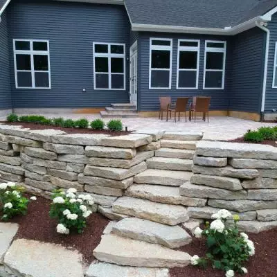 Ledge rock retaining wall and steps with patio and flower beds