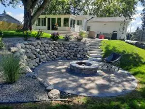 Brick fire pit on paver patio with ledge rock stepping stone and boulder retaining wall