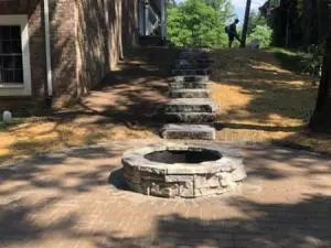 Brick fire pit with ledge rock steps connecting to round paver patio
