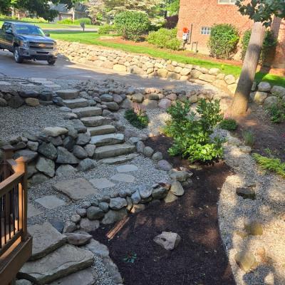 Natural boulder retaining wall with ledge rock walkway and egg rock filler